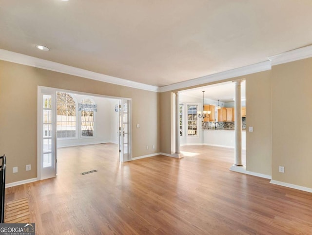 unfurnished living room with light hardwood / wood-style floors, crown molding, and an inviting chandelier