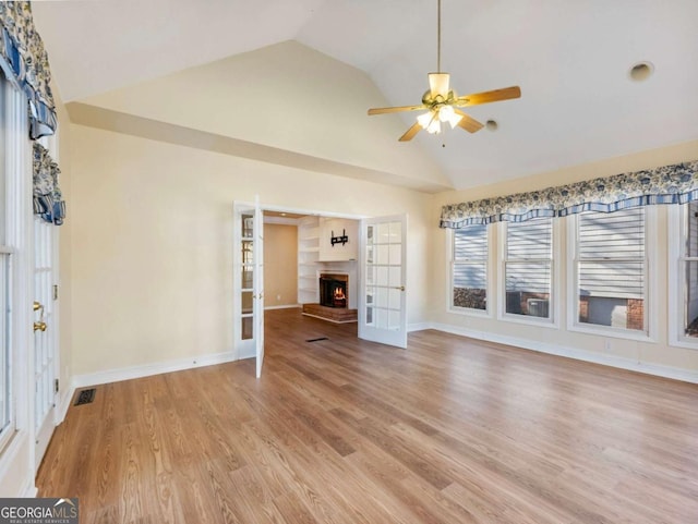 unfurnished living room with french doors, light wood-type flooring, ceiling fan, and lofted ceiling