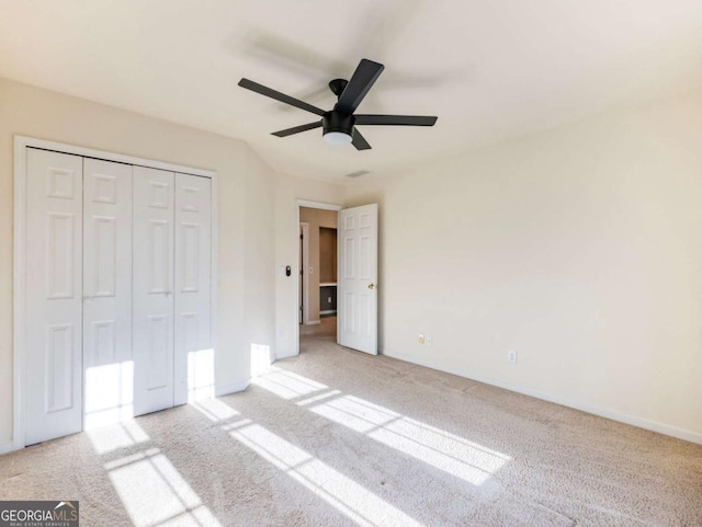 unfurnished bedroom featuring ceiling fan, light colored carpet, and a closet