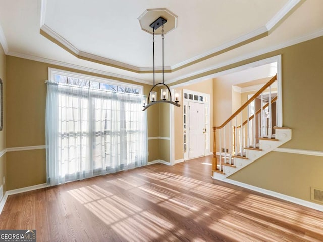 unfurnished dining area featuring a tray ceiling, hardwood / wood-style flooring, and ornamental molding