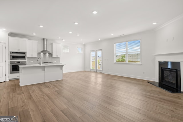 unfurnished living room with light wood-type flooring and ornamental molding