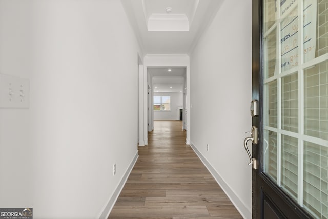 corridor with light wood-type flooring and crown molding