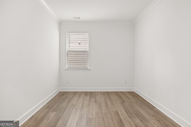 empty room featuring light wood-type flooring and ornamental molding