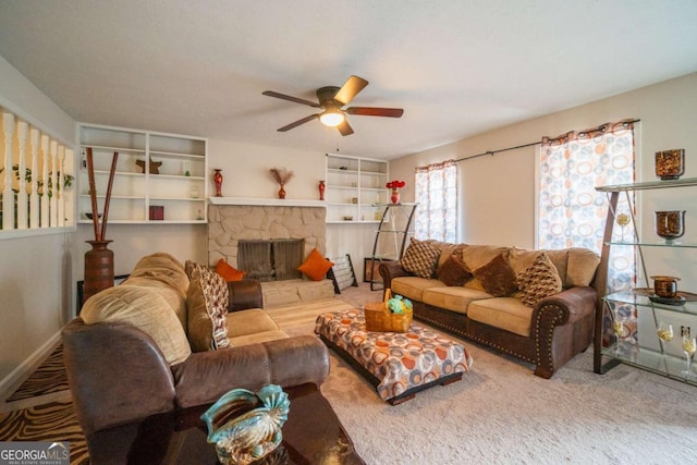 carpeted living room with ceiling fan and a stone fireplace