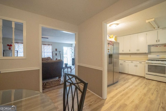 kitchen with light hardwood / wood-style floors, white range, white cabinetry, and stainless steel refrigerator with ice dispenser