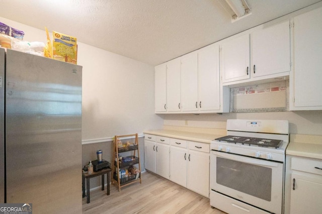 kitchen featuring white cabinets, stainless steel fridge, light wood-type flooring, a textured ceiling, and white gas stove