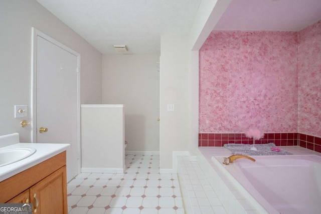 bathroom featuring a relaxing tiled tub and vanity