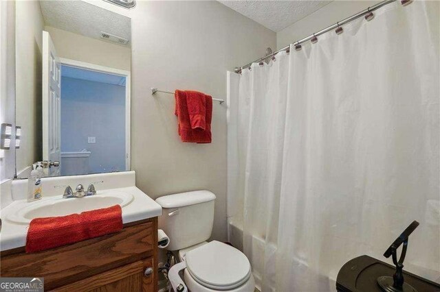 full bathroom with vanity, toilet, shower / bathtub combination with curtain, and a textured ceiling