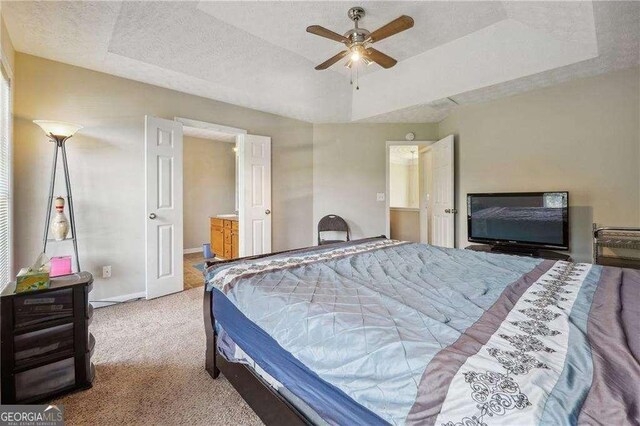 bedroom featuring a tray ceiling, ceiling fan, light carpet, and a textured ceiling