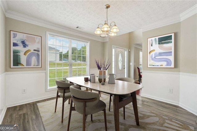 dining space with ornamental molding, dark hardwood / wood-style floors, a textured ceiling, and an inviting chandelier