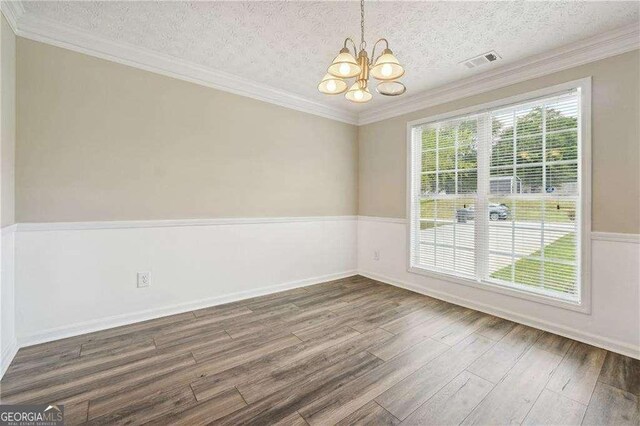 unfurnished room with crown molding, dark hardwood / wood-style flooring, a textured ceiling, and an inviting chandelier