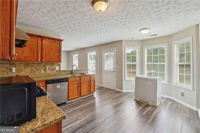 kitchen featuring dark wood-type flooring, sink, stainless steel dishwasher, decorative backsplash, and light stone countertops