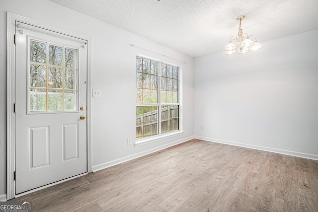 entrance foyer with hardwood / wood-style floors, a textured ceiling, and a notable chandelier