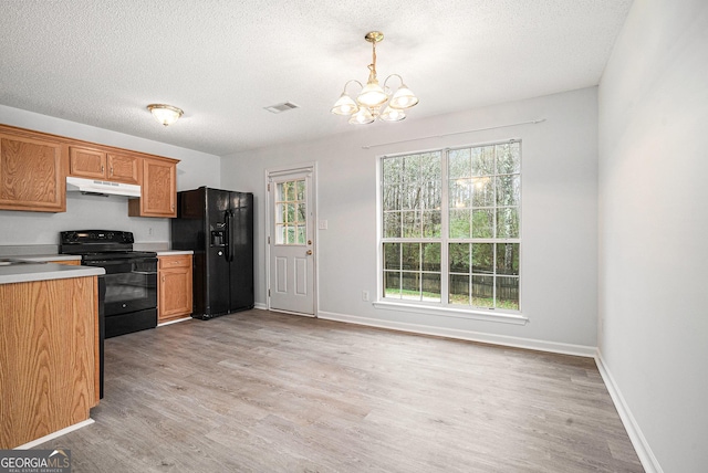 kitchen featuring an inviting chandelier, black appliances, light wood-type flooring, a textured ceiling, and decorative light fixtures