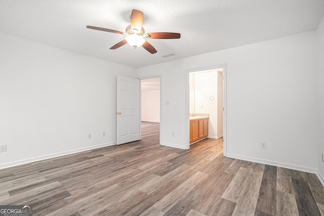 unfurnished bedroom featuring hardwood / wood-style flooring, ceiling fan, a textured ceiling, and connected bathroom