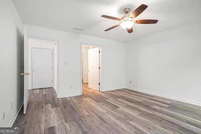 unfurnished bedroom with a textured ceiling, dark hardwood / wood-style flooring, and ceiling fan