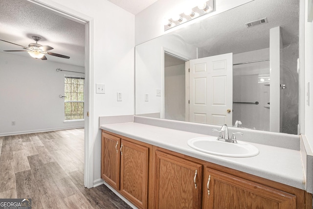 bathroom with ceiling fan, hardwood / wood-style floors, vanity, and a textured ceiling