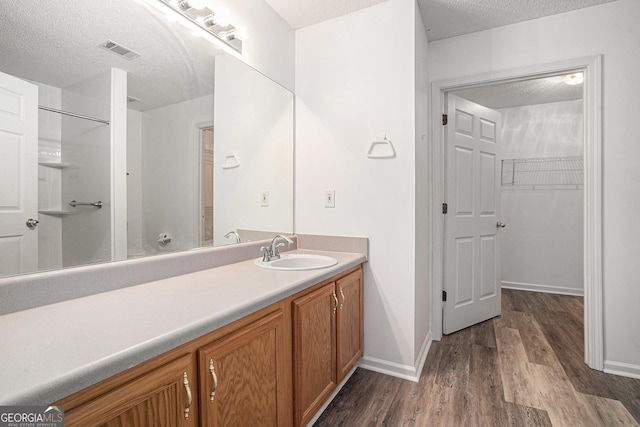 bathroom with hardwood / wood-style floors, vanity, and a textured ceiling