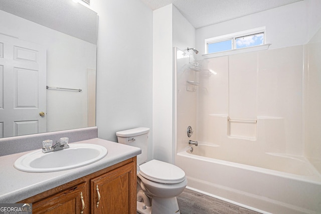 full bathroom featuring vanity, a textured ceiling, washtub / shower combination, hardwood / wood-style floors, and toilet