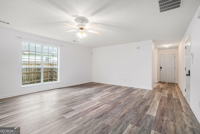 empty room with hardwood / wood-style floors, ceiling fan, and a textured ceiling