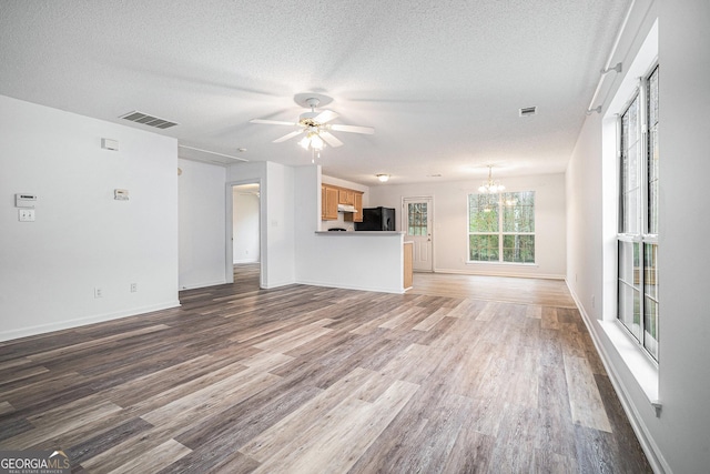 unfurnished living room featuring hardwood / wood-style floors, ceiling fan with notable chandelier, and a textured ceiling