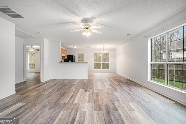 unfurnished living room with a textured ceiling, hardwood / wood-style flooring, and a notable chandelier