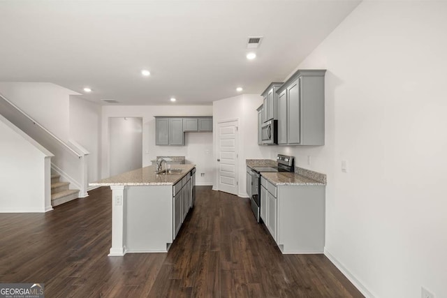 kitchen featuring gray cabinetry, light stone countertops, sink, a kitchen island with sink, and appliances with stainless steel finishes