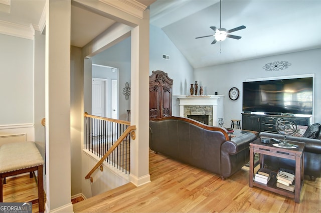 living room with light hardwood / wood-style floors, a stone fireplace, ceiling fan, and lofted ceiling