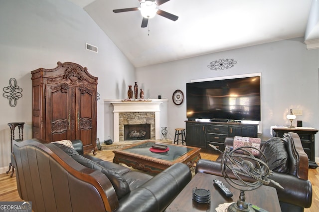 living room featuring ceiling fan, vaulted ceiling, a fireplace, and light hardwood / wood-style flooring