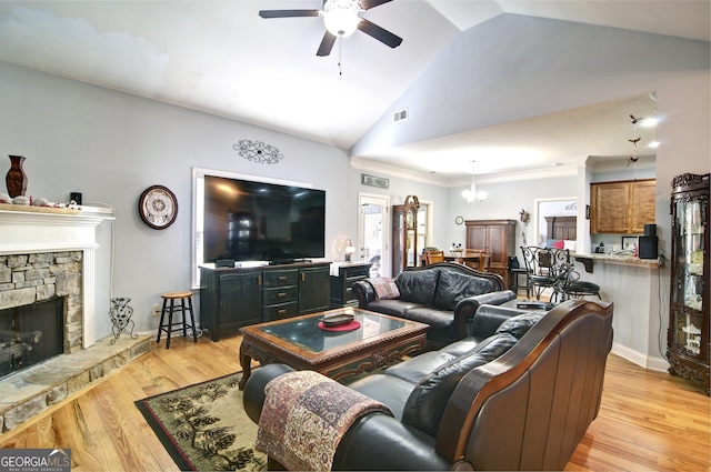 living room featuring ceiling fan with notable chandelier, light hardwood / wood-style floors, lofted ceiling, and a fireplace