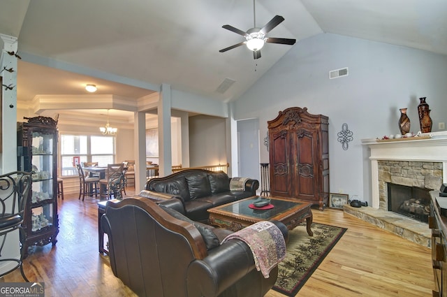 living room featuring a fireplace, high vaulted ceiling, wood-type flooring, and ceiling fan with notable chandelier