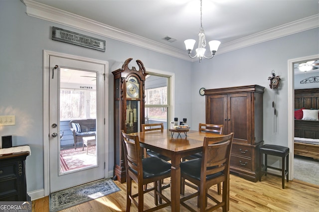 dining space with a chandelier, ornamental molding, and light hardwood / wood-style flooring