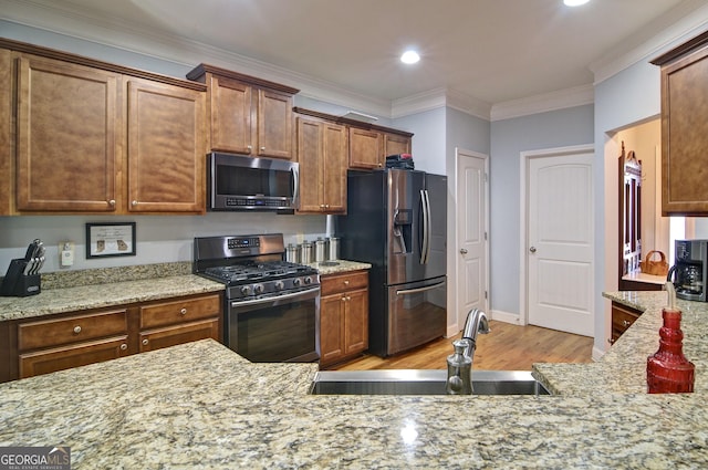 kitchen featuring light stone countertops, ornamental molding, stainless steel appliances, sink, and light hardwood / wood-style flooring