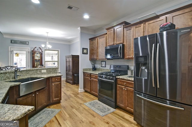 kitchen with light stone countertops, sink, a chandelier, pendant lighting, and appliances with stainless steel finishes