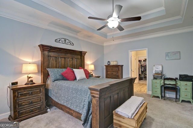 carpeted bedroom with a tray ceiling, a walk in closet, ceiling fan, and a closet