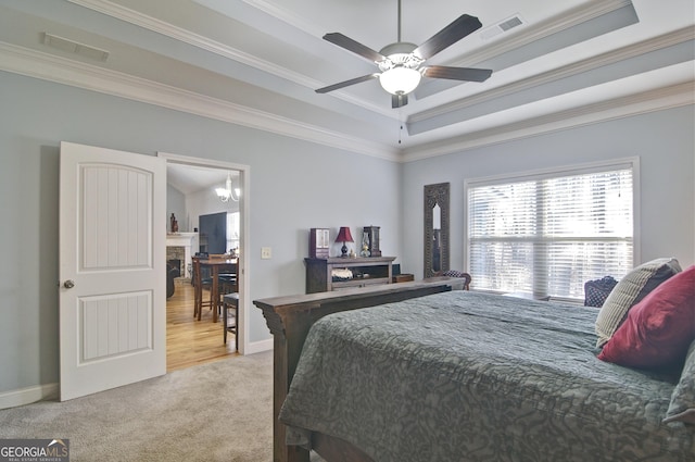 bedroom with ornamental molding, ceiling fan with notable chandelier, light colored carpet, and a tray ceiling