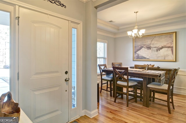 entryway with crown molding, a notable chandelier, and light wood-type flooring