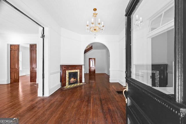 unfurnished living room with dark hardwood / wood-style flooring, a fireplace, and an inviting chandelier