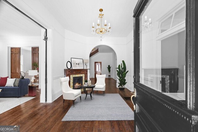 198 Dearing St, Athens, GA 30605 - sitting room with arched walkways, a warm lit fireplace, an inviting chandelier, and dark wood finished floors