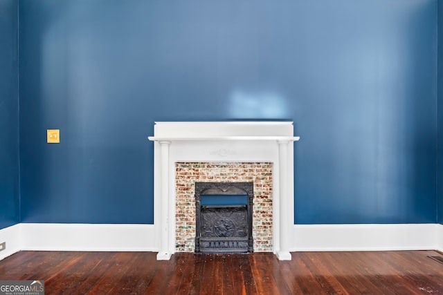 unfurnished living room featuring wood-type flooring and a brick fireplace