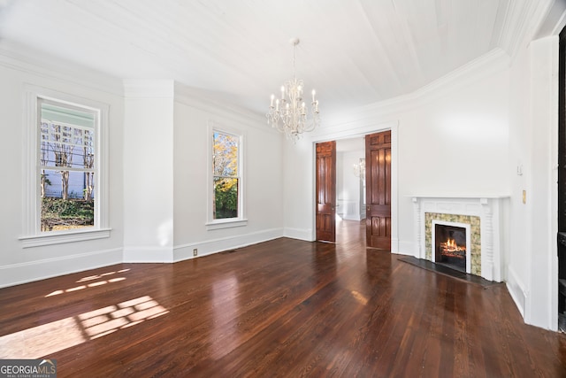 unfurnished living room featuring ornamental molding, dark hardwood / wood-style floors, a wealth of natural light, and a notable chandelier