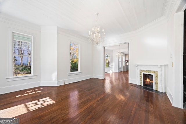 unfurnished living room with a tile fireplace, a wealth of natural light, dark wood-type flooring, and an inviting chandelier