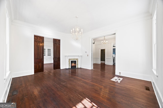 unfurnished living room featuring dark hardwood / wood-style floors, crown molding, and an inviting chandelier