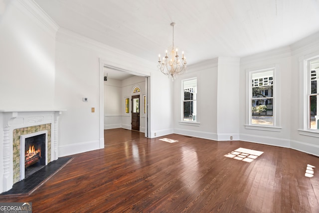 unfurnished living room with dark hardwood / wood-style flooring, ornamental molding, a tile fireplace, and an inviting chandelier