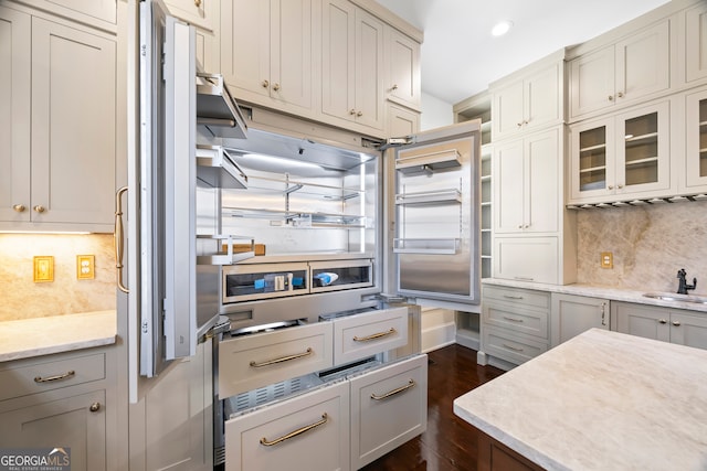 kitchen featuring backsplash, light stone countertops, sink, and dark hardwood / wood-style floors