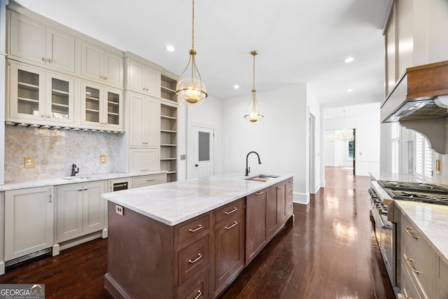 kitchen featuring light stone countertops, sink, pendant lighting, a kitchen island with sink, and high end range