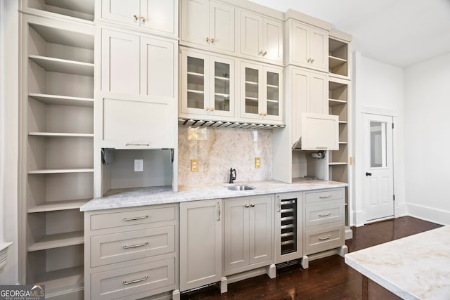 kitchen featuring light stone countertops, sink, dark wood-type flooring, beverage cooler, and tasteful backsplash