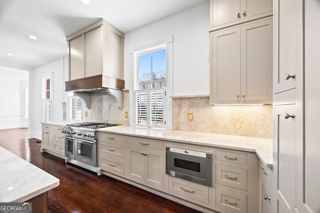 kitchen featuring decorative backsplash, dark hardwood / wood-style flooring, light stone counters, custom exhaust hood, and double oven range