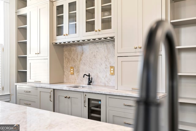 kitchen with sink, wine cooler, gray cabinets, tasteful backsplash, and light stone counters