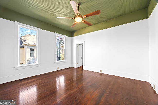 empty room featuring a wealth of natural light, dark wood-type flooring, and ceiling fan